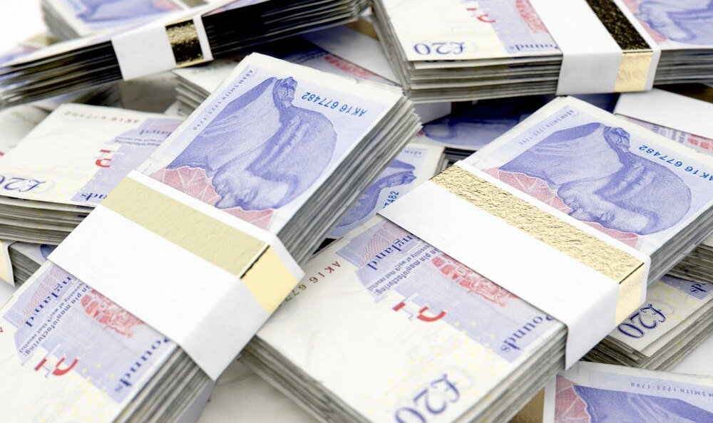 British Pound: A pile of randomly scattered bundles of british pound banknotes.