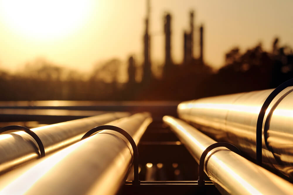 commodities: golden sunset in crude oil refinery with pipeline system.